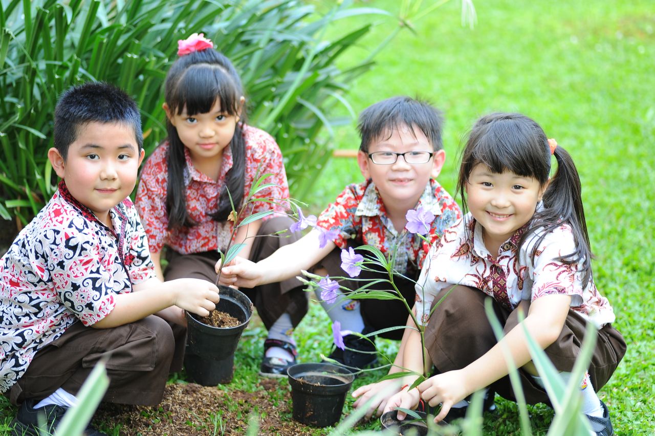 Group of happy children planting flowers together in a garden.